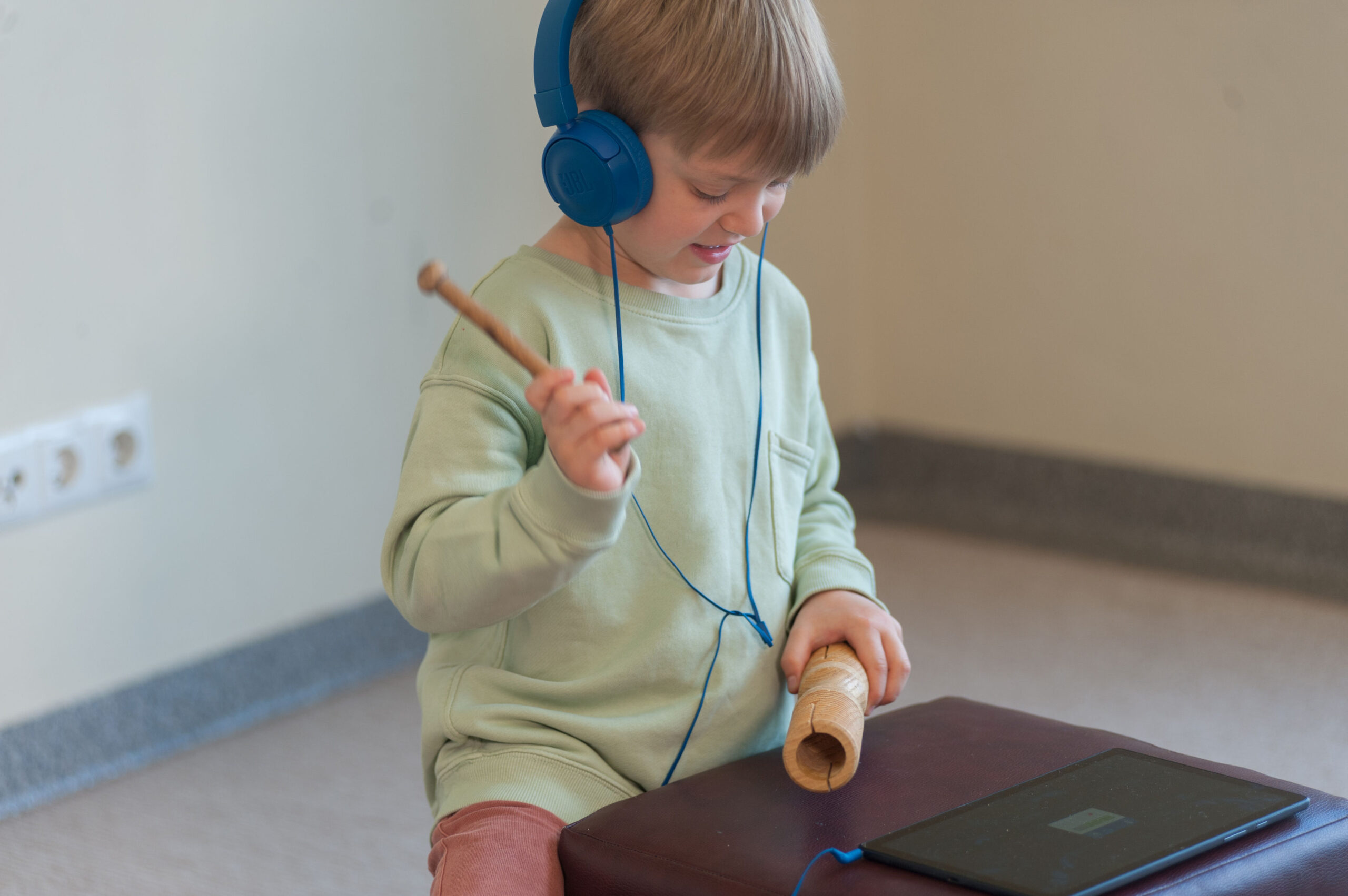 Vaikas su ausinėm ir instrumentu